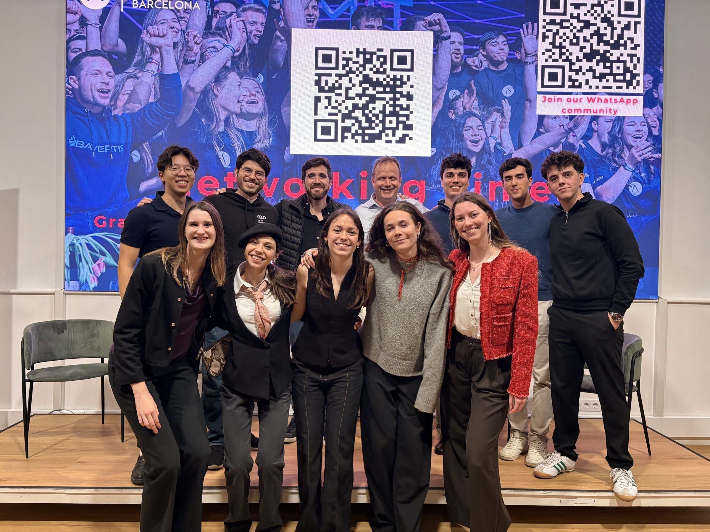The team and finalists posing on stage in front of a screen with QR codes