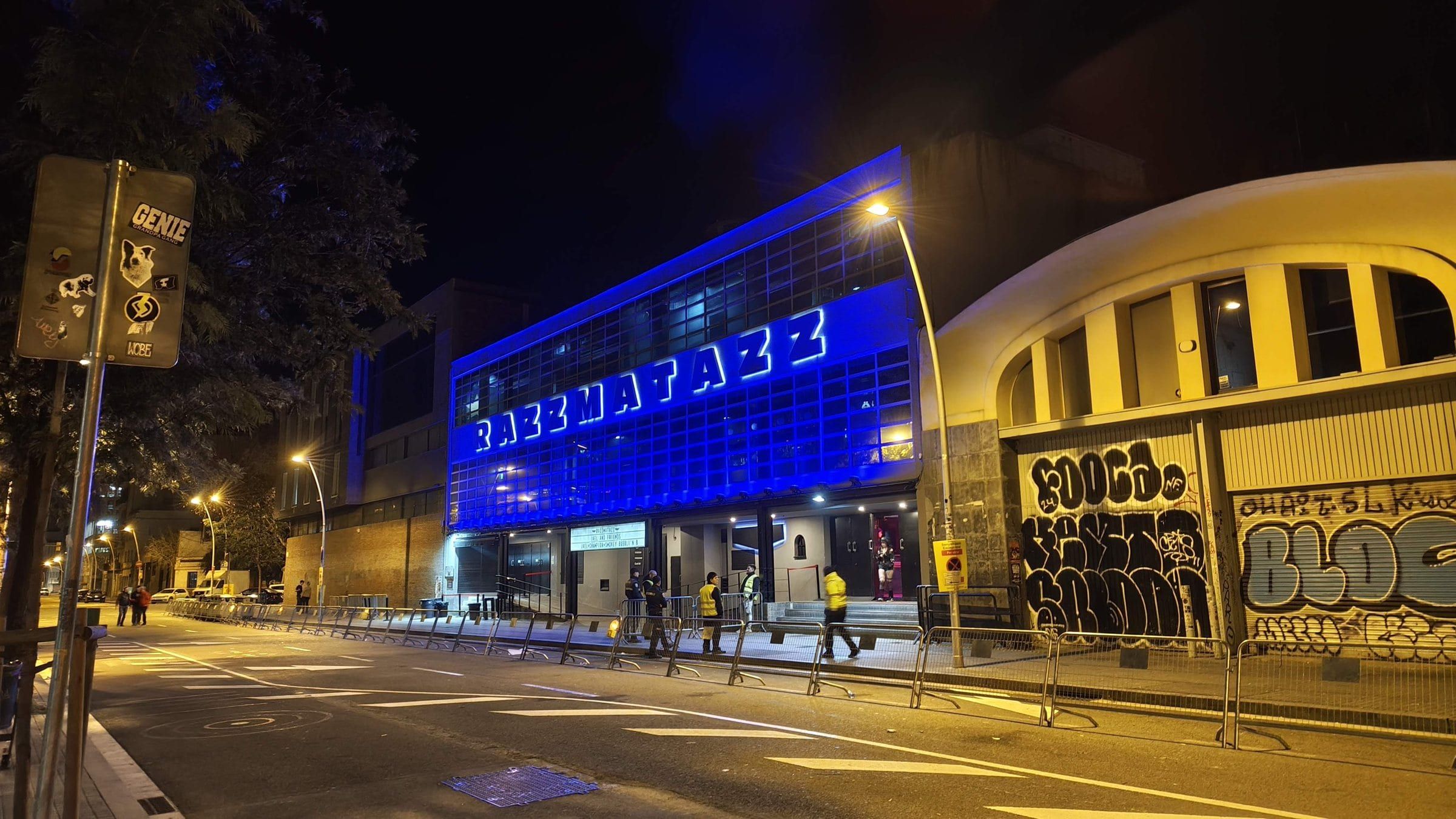 The Razzmatazz club lit blue at night across the street from the hackathon venue