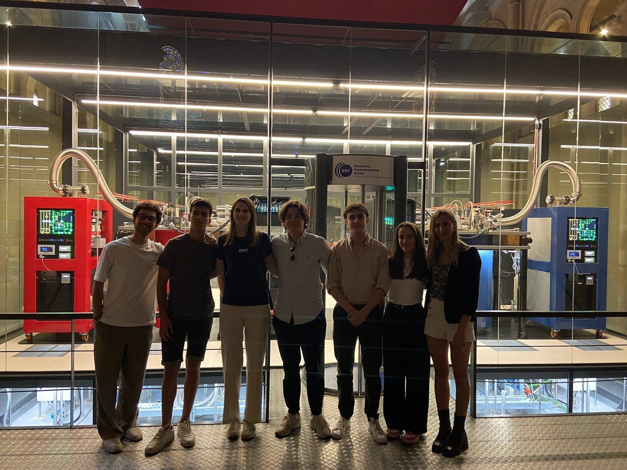 Members lined up in front of the glass-walled machine room at the Barcelona Supercomputing Center