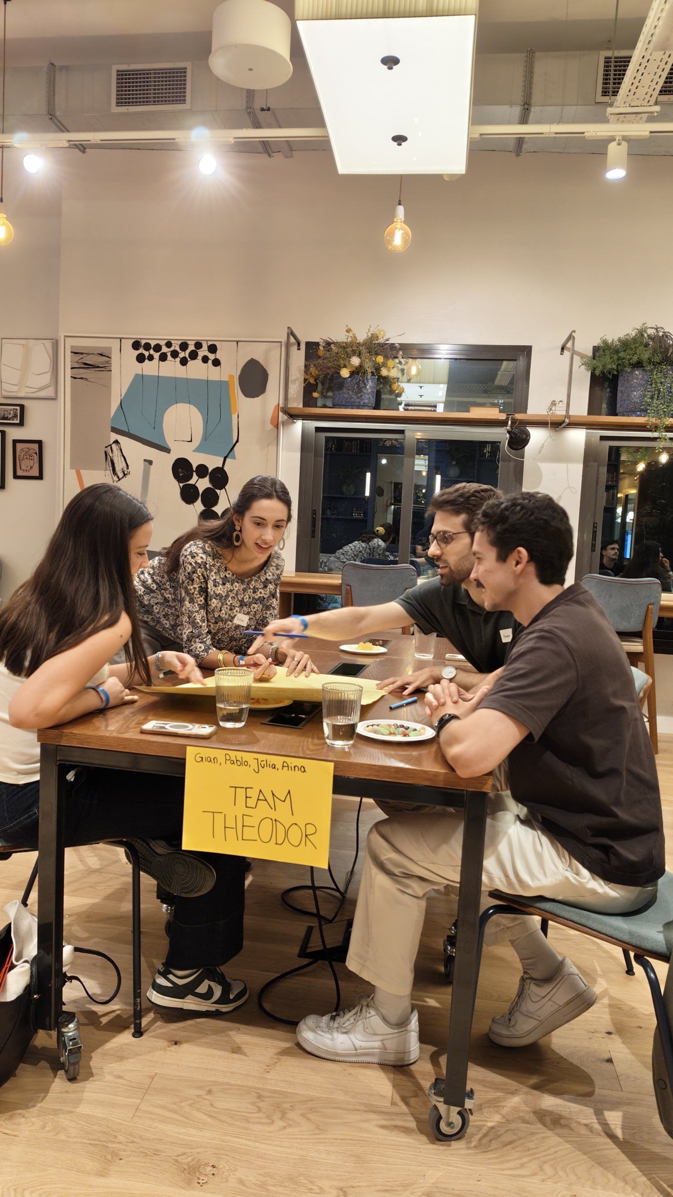 Team Theodor laughing around a table with snacks and big sheets of paper