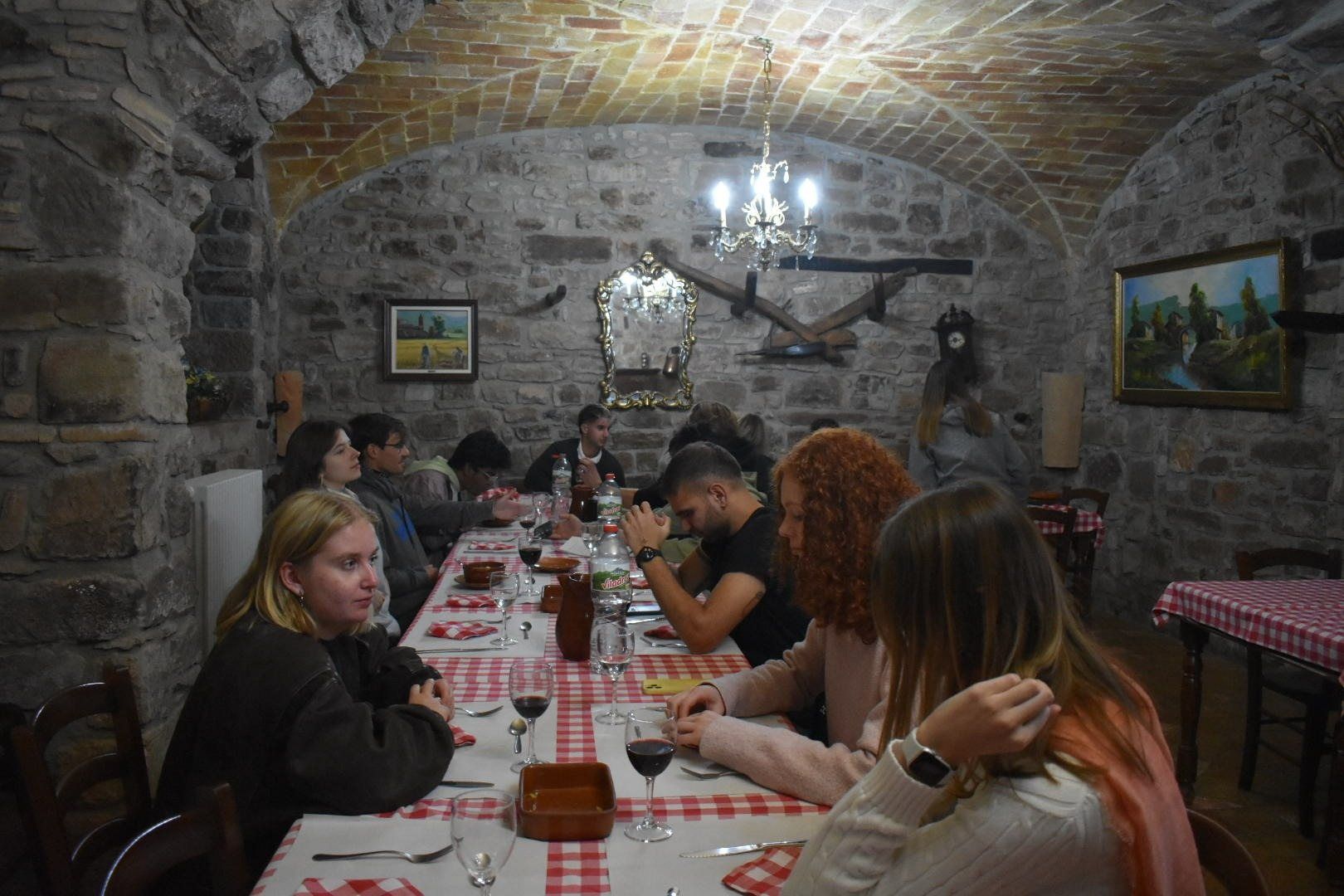 A long dinner table with red checked tablecloths in a stone-vaulted room
